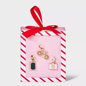 Close-up of 18K gold plated charms including a bicycle and camera in a pink gift box