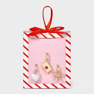 Close-up of heart pearl, envelope, and bow charms in a festive pink gift box