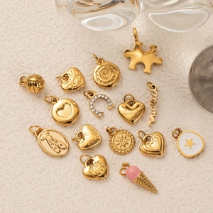 Assorted 18K gold plated DIY charms with heart, horseshoe, and star designs on beige tray