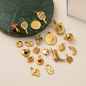 Golden 18k plated stainless steel charms with enamel and zircon details on marble