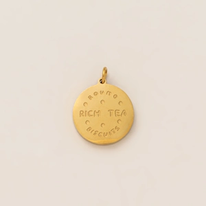 Detailed macro shot of a gold biscuit-shaped round pendant with rich tea biscuit engraving