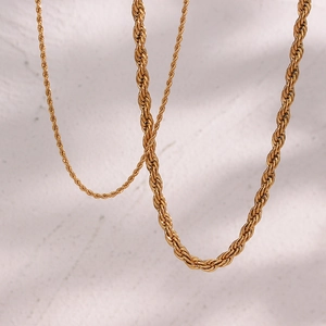 Dettaglio macro di tre catene a corda intrecciata in acciaio inossidabile placcato oro 18K lucido
