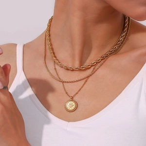 Close-up of layered 18K gold-plated chunky twist chain and sun pendant on a model