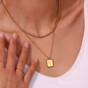Dettaglio ravvicinato della collana a doppio strato dorata con ciondolo floreale su modella