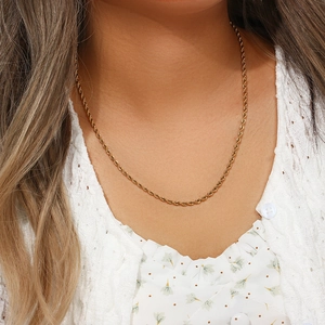 Gros plan d'un collier chaîne torsadée en acier inoxydable plaqué or 18 carats sur un mannequin