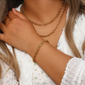 Détail de l'ensemble collier et bracelet à chaîne torsadée en acier plaqué or 18 carats