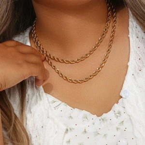 Détail de deux chaînes torsadées en acier inoxydable plaqué or 18K portées par un mannequin