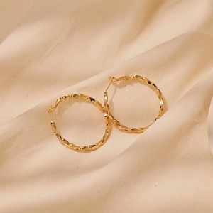 Macro shot of 18K gold plated hoop earrings featuring a faceted geometric texture finish