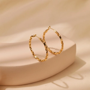 Detailed close-up of 18K gold-plated hoop earrings with unique geometric faceted textures