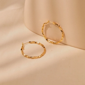 Macro view of large 18K gold plated hoop earrings with twisted metal texture