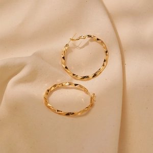 Macro shot of 18K gold plated hoop earrings with twisted geometric metal texture