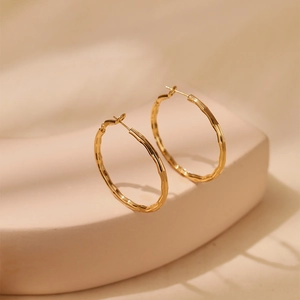 Chic 18K gold plated hoop earrings with textured bamboo design on a warm beige background