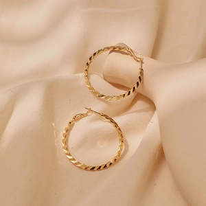 Macro shot of gold-plated hoop earrings featuring elegant twisted textured design