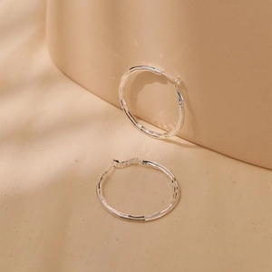 Detailed macro view of large textured hoop earrings with wave surface and pin closure