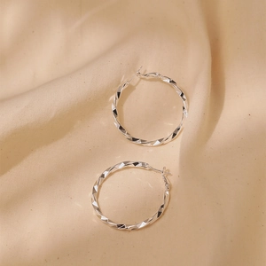 Detailed macro view of S925 silver hoop earrings with twisted geometric facets surface