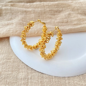 Unregelmäßige gewundene Gold-Creolen mit 18K Vergoldung auf weißem Keramikteller