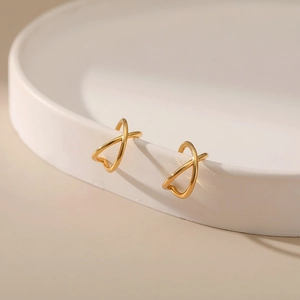 Macro view of minimalist 18K gold plated brass ear cuff with crisscross X-shaped design