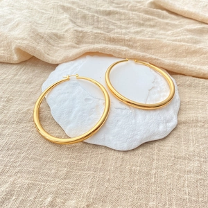 Detail von klobigen goldenen Creolen mit poliertem Finish auf Steindisplay