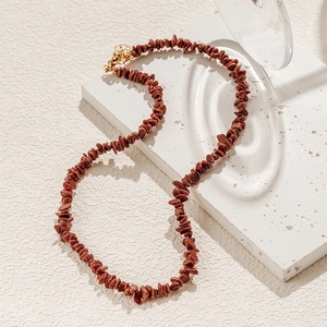 Detailopname van bohemian rode zandstenen ketting met gouden kreeftsluiting op witte steen
