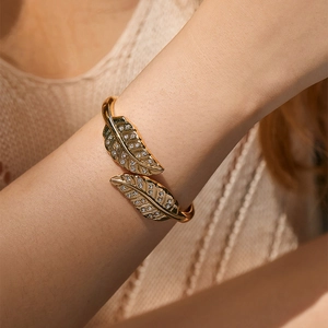 Detail of gold-plated leaf bangle featuring pavé-set sparkling crystals on woman wrist