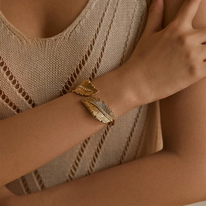 Detailed view of a gold feather cuff bracelet with sparkling crystal inlay on model
