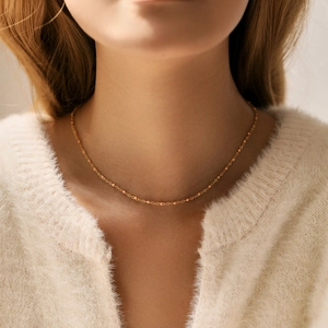 Dettaglio della collana girocollo in ottone placcato oro 18K con perline su una modella