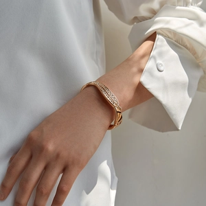 Detailed view of a gold-plated open cuff bracelet with pavé crystal leaf patterns