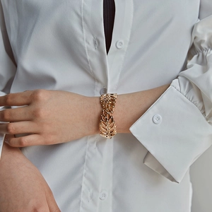 Close-up of gold leaf-shaped cuff bracelet with micro-pave crystals on a model wrist