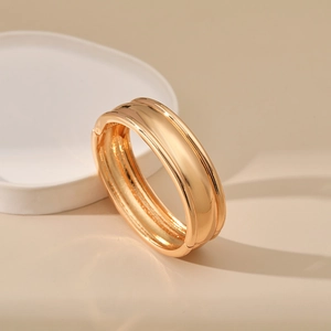 Detailed close-up of a polished gold-finished bangle featuring a secure hinged closure