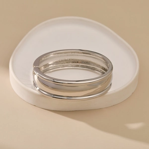 Polished silver cuff bracelet featuring a wide band with elegant convex edge details
