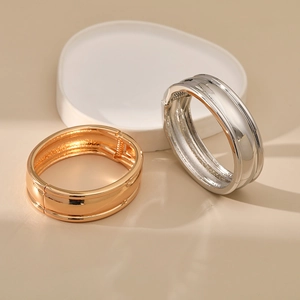 Close-up of gold and silver minimalist bangle bracelets with spring hinge design