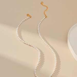 Detail van elegante kleine witte parelketting met verstelbare gouden karabijnsluiting