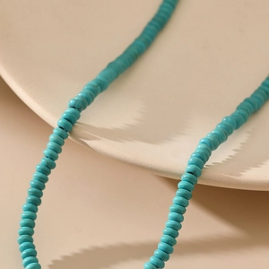 Macro detail van een boheemse turkooizen kralenketting op een wit keramisch bord