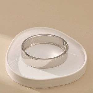 Detail view of silver wide cuff bangle showing hinged closure and mirror-polished surface
