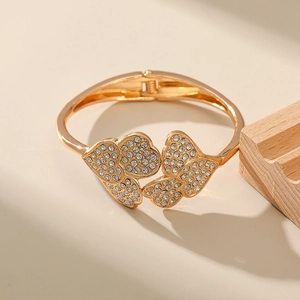 Detail of golden heart-shaped bangle featuring paved white zirconias and spring hinge closure