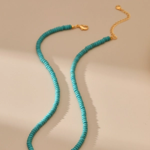 Detail van turquoise kralenketting met vergulde karabijnsluiting en verstelbare ketting