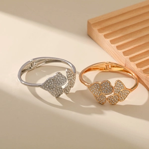 Detail of gold and silver hinged bracelets with interlocking heart crystal patterns
