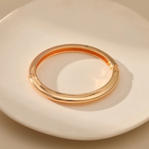 Detailed close-up of a minimalist gold hinged bangle with a polished mirror finish surface