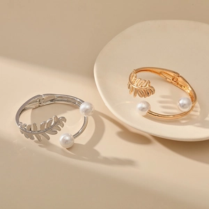 Detail view of leaf pattern gold and silver bangles with white pearl accents