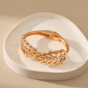 Detail of golden hollow leaf bracelet with sparkling rhinestones and hinge closure