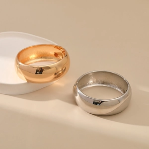 Detailed view of polished wide bangles with hinge mechanism in gold and silver finish