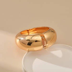 Detailed close-up of wide gold minimalist bangle with polished mirror finish and hinge closure