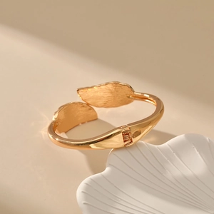 Detail of golden leaf bracelet showing the brushed metal texture and spring hinge mechanism