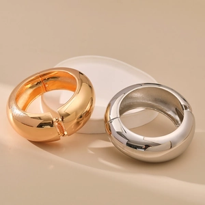 Detailed view of polished gold and silver metal bangles with spring hinge closure