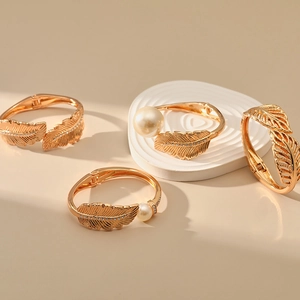 Detailed close-up of gold leaf-shaped alloy bracelets with faux pearls and rhinestones