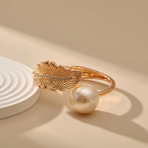 Detail of gold-tone feather bangle with sparkling crystals and a large cream pearl