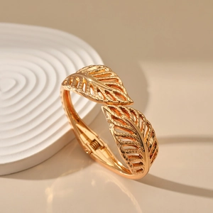 Close-up of golden leaf-shaped bangle featuring intricate vein texture and spring hinge