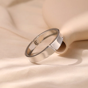 Close-up of sleek silver minimalist hinged bangle on aesthetic warm fabric background