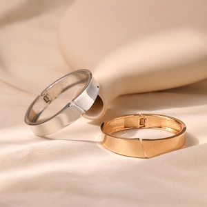 Detail of minimalist gold and silver bangles with a hinge closure on soft fabric