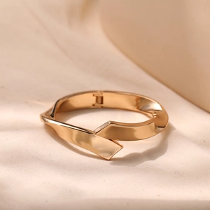 Detailed view of a gold-toned twisted metal bracelet with a polished mirror finish